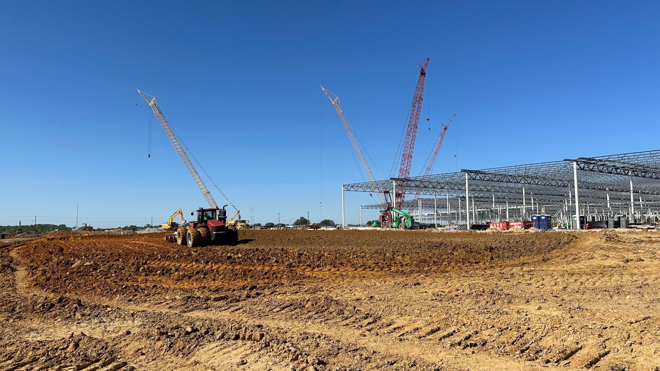 A construction site with cranes in the background hums with activity, resembling a giant mechanical plant.