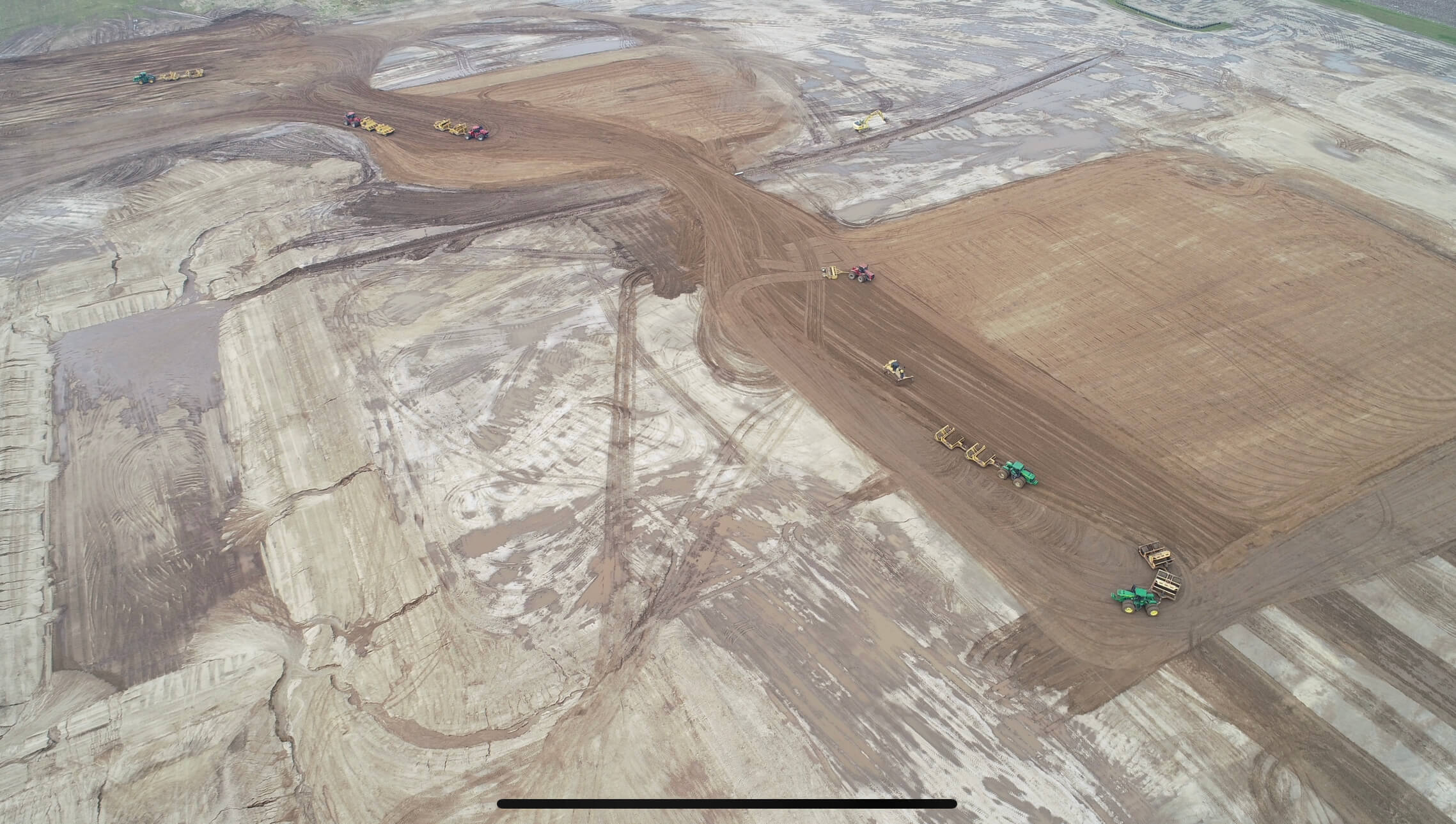 An aerial view of a dirt field with tractors.