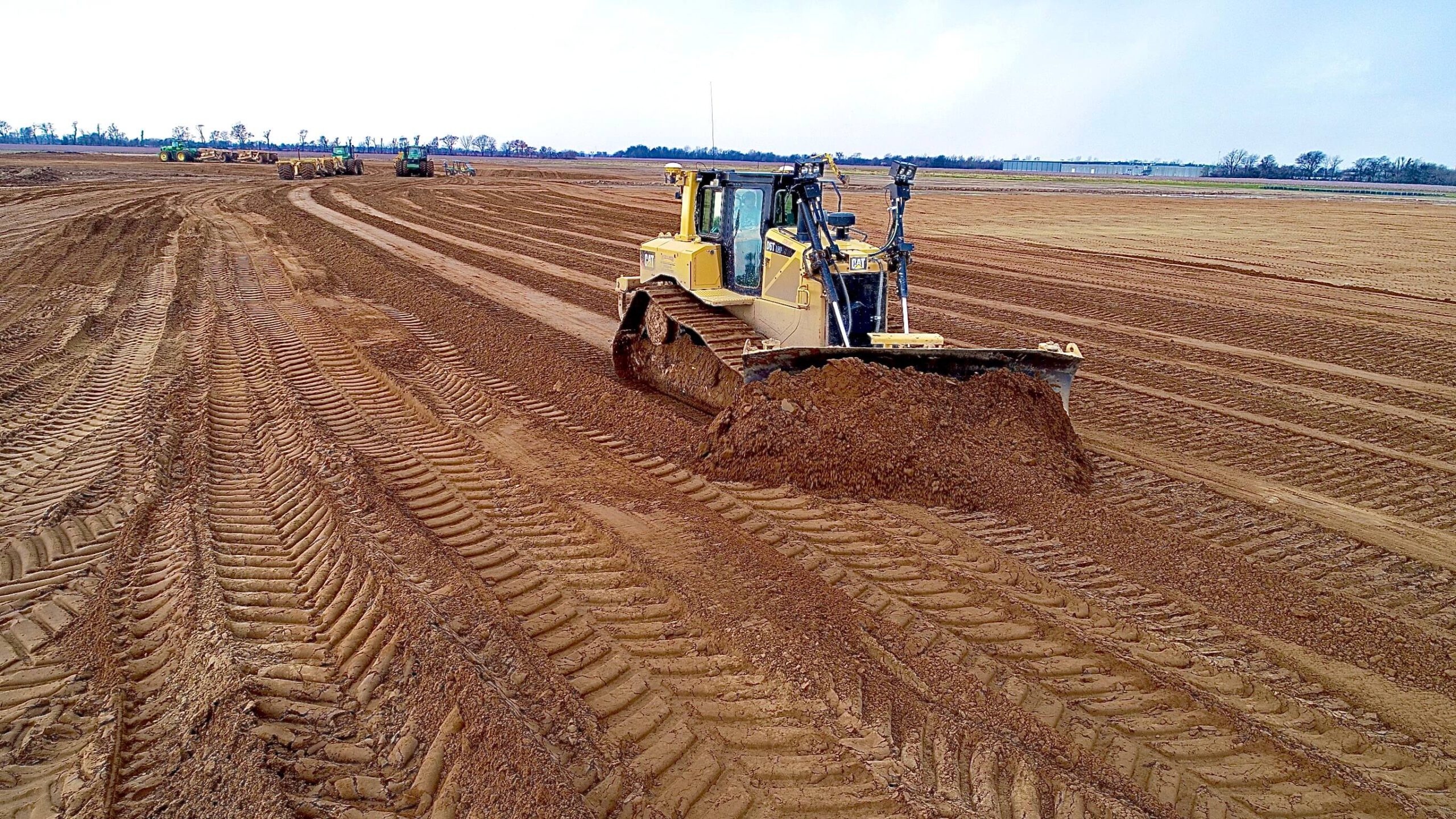 A bulldozer in a large open field of dirt.