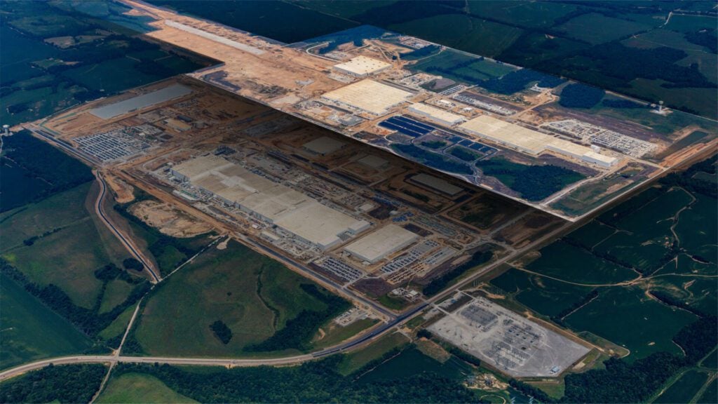 Aerial view showing the construction stages of the large Ford industrial complex, known as Blue Oval City, surrounded by green fields and forest. The image layers progress from an early foundational stage to a more developed structure, illustrating the site's transformation.