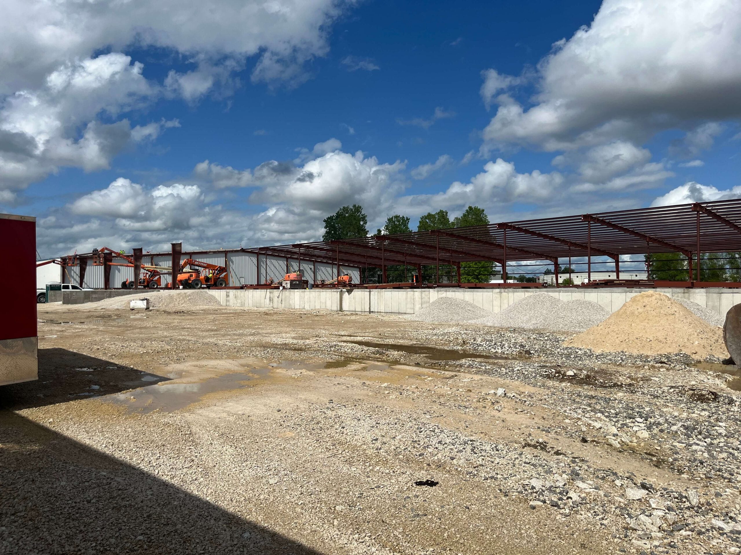 SEMO Box’s construction site for a new facility expansion, showcasing steel framing, construction equipment, and building materials under a partly cloudy sky.